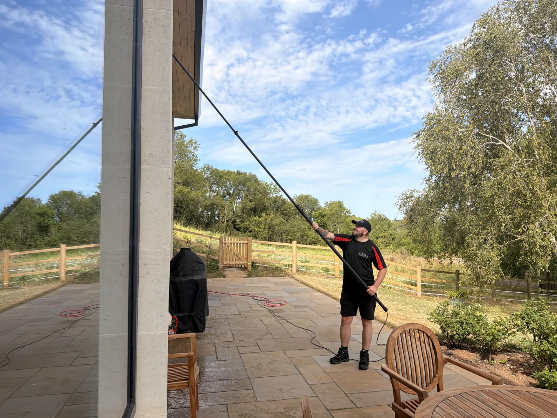 A Somerset Window Cleaning technician cleaning double-height windows with a reach and wash pole